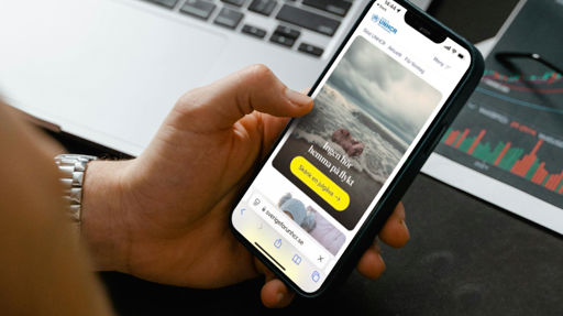 Hand som håller i en telefon med hemsidan Sverige för UNHCR